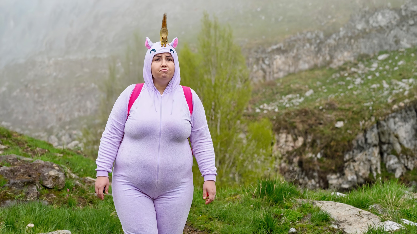 a pouting plump adult Russian woman, wearing unicorn costume, exploring a spring mountain ravine, ground fog