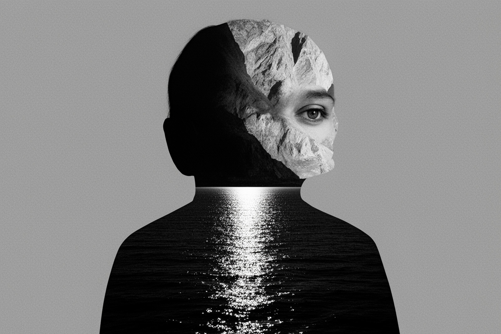 Black-and-white surrealist double exposure portrait. The central subject is the silhouette of a person's head and shoulders against a flat, neutral grey background. The interior of the head is a composite of textures; the right side reveals a light-colored, craggy mountain face where a single, realistic human eye gazes outward. The left side is a darker, obscured mass. The subject's torso is seamlessly replaced by a dark, shimmering sea under moonlight, with a bright, glittery vertical reflection of light dancing across the water's surface. The composition is stark and centered, utilizing high contrast to create a moody, contemplative atmosphere. The image has a grainy, film-like texture with no color, emphasizing the play between light and shadow within the surreal forms.