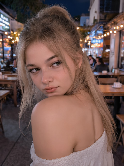 y0ngcut1,POV candid close-up shot from behind, capturing a young woman with long, flowing blonde hair tied neatly into a high ponytail, walking away from the viewer through the dimly lit outdoor patio of a cozy, rustic café at night. She’s mid-stride, slightly turning her head over her shoulder with a playful, slightly annoyed yet irresistibly cute expression — one eyebrow raised, lips pursed in mock frustration, eyes half-lidded with a smirk. The ambient lighting is warm and moody — soft string lights flicker overhead, casting gentle glows on her hair and skin, while the background features blurred neon signs, wooden tables, and the quiet hum of late-night café life. A faint breeze ruffles her ponytail as she walks, and the shallow depth of field keeps the focus tight on her face and upper body, making her expression and movement feel intimate and spontaneous. The scene feels candid, unposed, and emotionally charged — a fleeting moment of youthful rebellion or playful annoyance caught in the golden hour of night. Style: cinematic realism, soft bokeh, shallow depth of field, high detail, 8K resolution, natural skin tones, ambient lighting, slightly grainy film texture for realism.