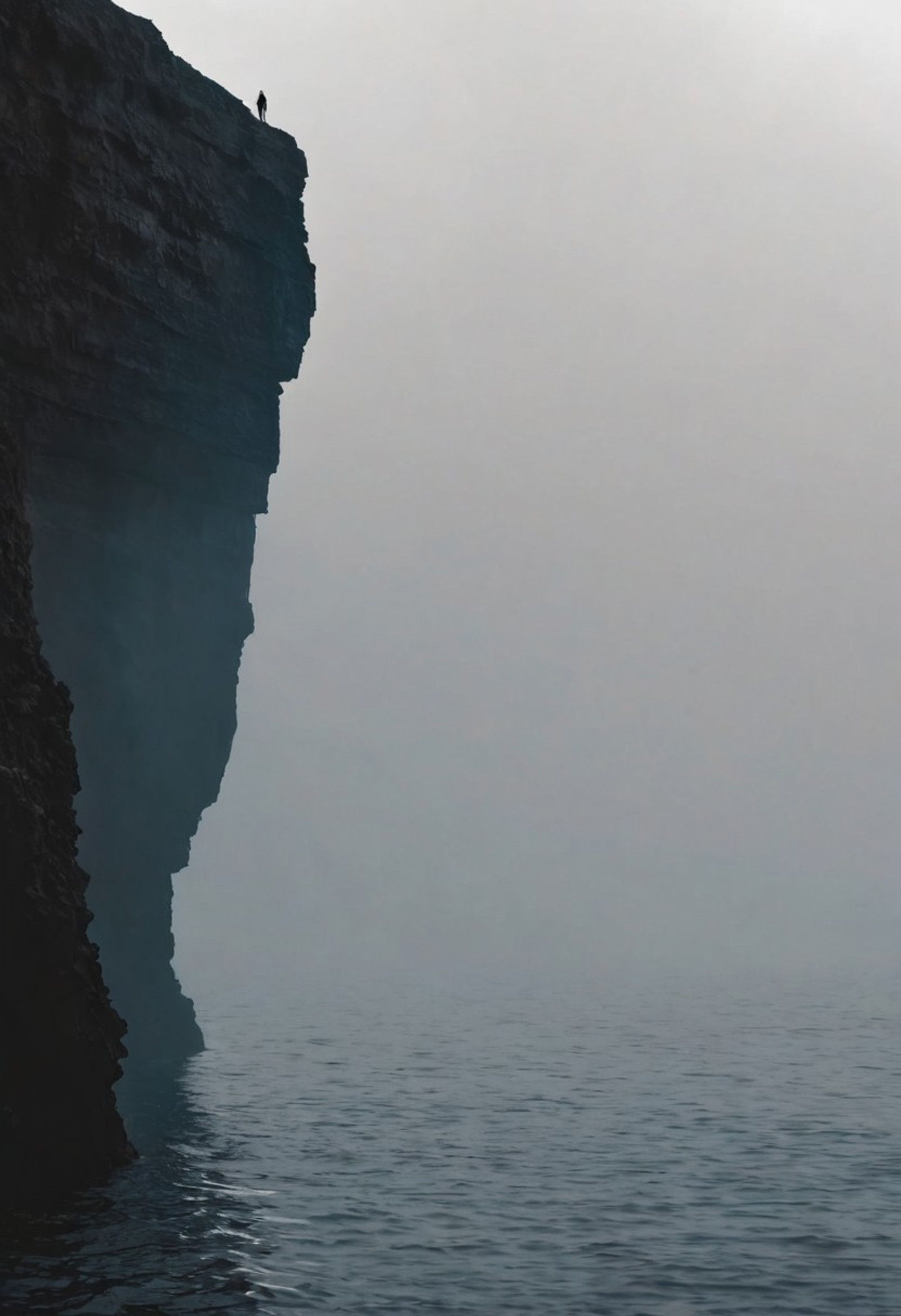 The SIlhouetted person to the edge of the cliff. high contrast, a huge cliff in the middle, big lake in between, mist, minimalism, a huge waterfall from the cliff, a silhouetted person on the edge. vast deep blue ocean.